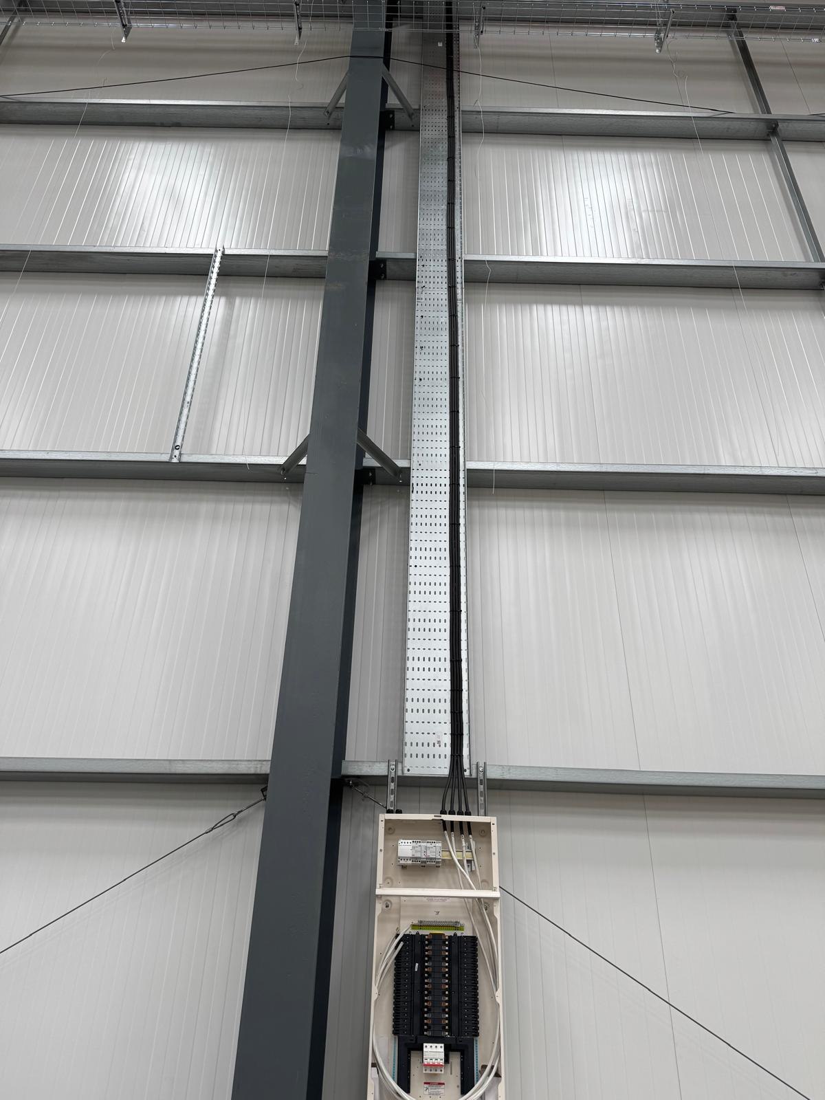 Cable containment run feeding a distribution board in a warehouse