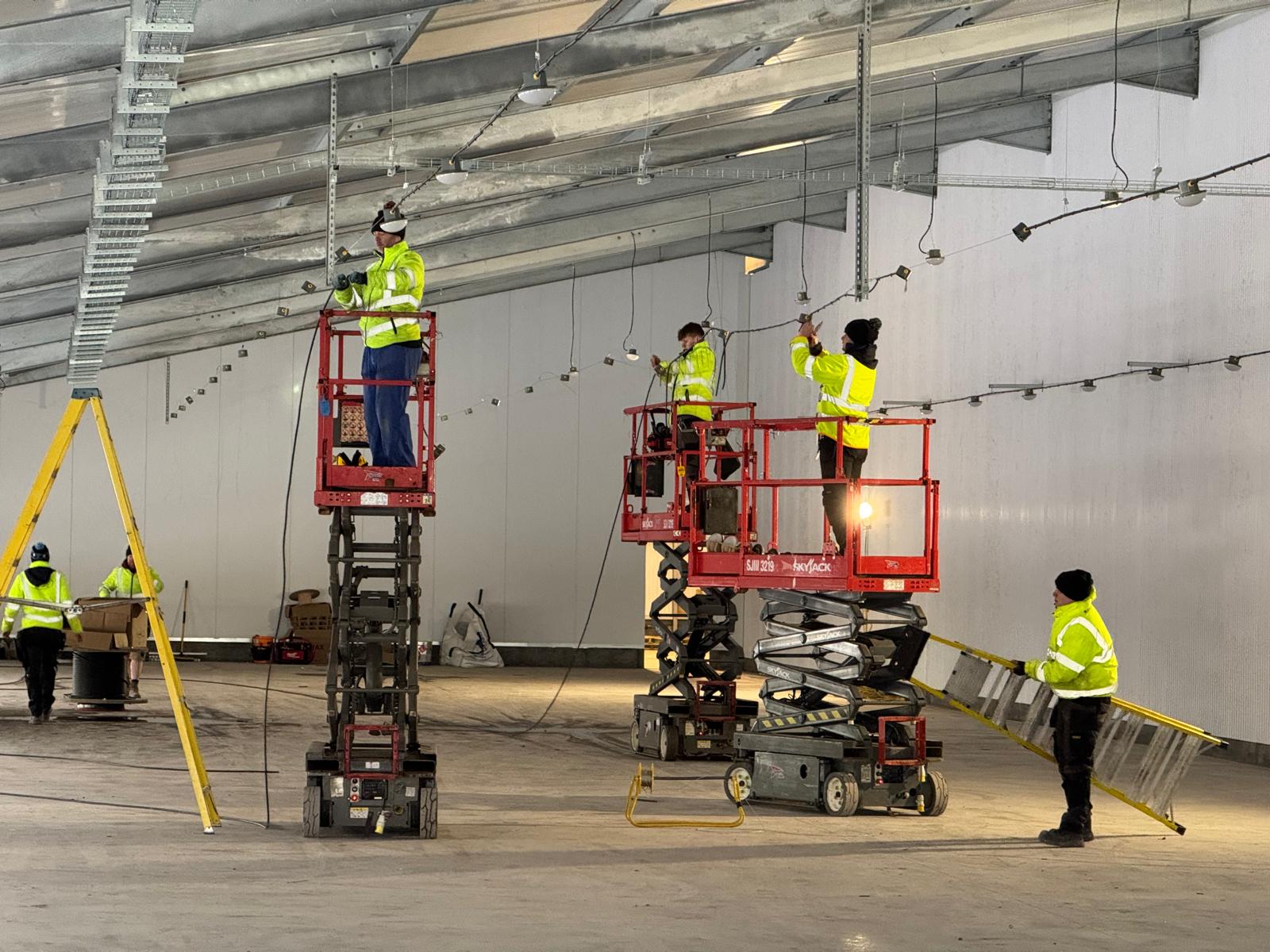 Commercial Electrical Services: WPP Electrical team installing lighting from scissor lifts in a new commercial warehouse
